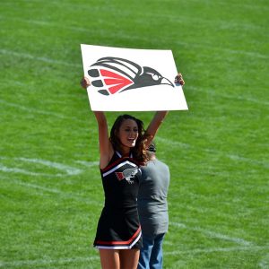 Raider Cheerleader Holding Sign With Hawk Logo
